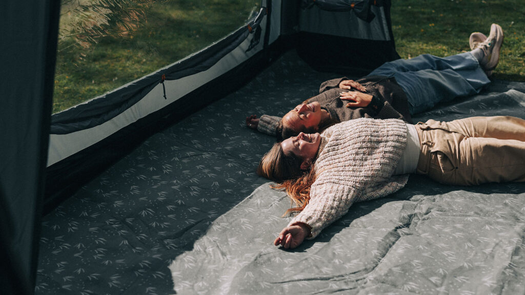 A couple lying on the groundsheet of their Kampa tent on a camping trip