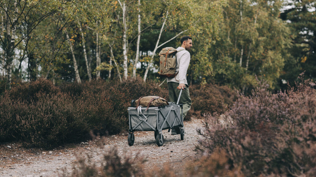 A man pulling a trolly loaded with Kampa camping equipment on the way to the campsite